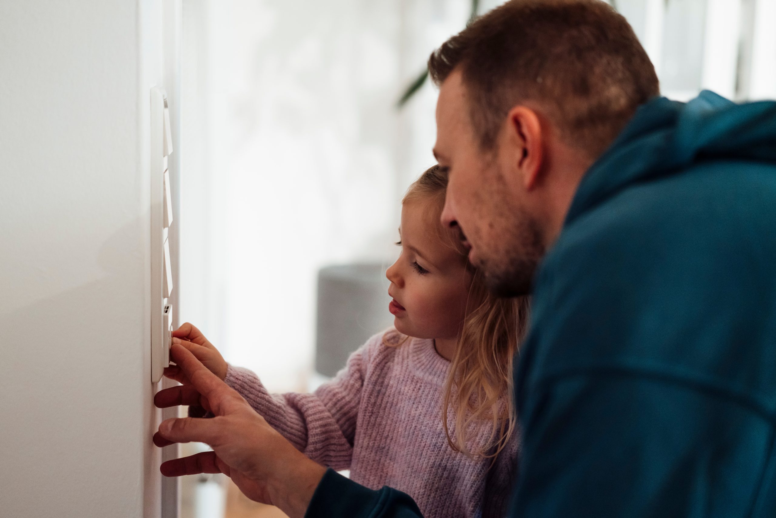 Girl,And,Father,Adjusting,Temperature,On,Thermostat,At,Home